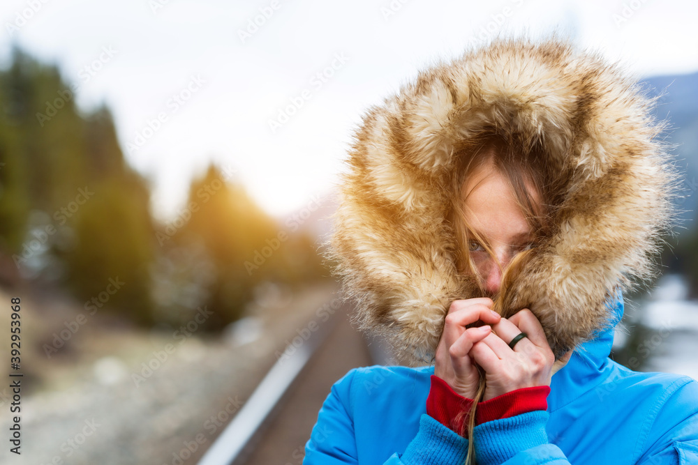 Wall mural pretty young caucasian woman hiding under her fur hood in winter. having fun at the mountain during 