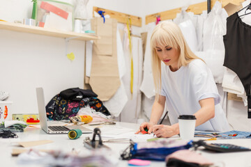 Young fashion designer working on her atelier. Fashion Design Studio with Working Personal...