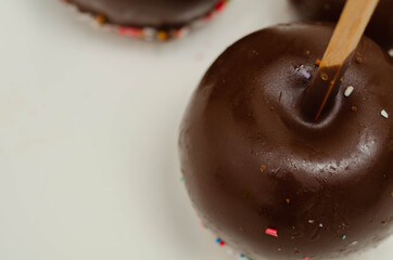 Candy apple coated with milk chocolate and covered with colorful sweet sprinkles