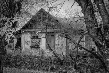 An old, abandoned house with boarded-up windows. Black and white photo