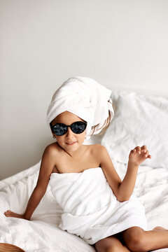 Portrait of a stylish little girl in sunglasses and with her hair wrapped in a bath towel.