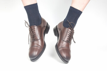 Male legs in socks and brown classic leather shoes on a white background