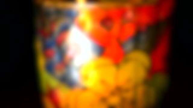 Blurred background. candle flame shines in a colorful candlestick closeup
