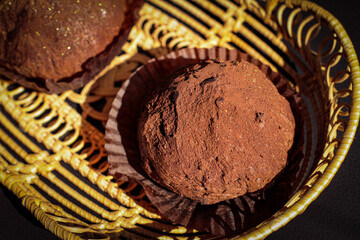 Two delicious handmade chocolates truffle in a wicker plate on black background