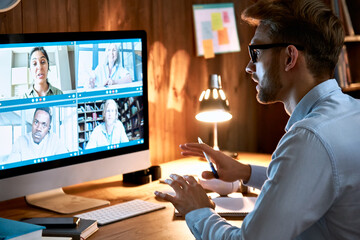 Businessman executive leading virtual team meeting on video conference call using computer working from home office talking to diverse colleagues in remote videoconference online social distance chat.