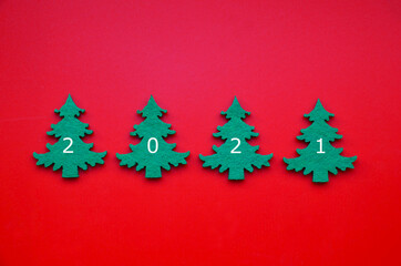 New Year 2021 greeting card with green fir trees on red background. Winter holidays minimal flat lay concept for design.Selective focus.