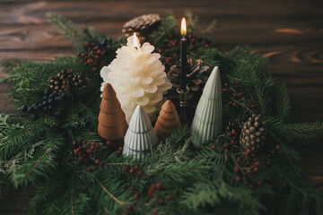 Christmas table setting decor, modern wreath, little trees and candles on rustic wooden table