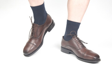Male legs in socks and brown classic shoes on a white background