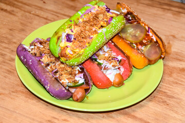 hot dogs assorted multi-colored buns different toppings on green plate