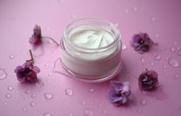 white jar with cream on a pink background decorated with flowers