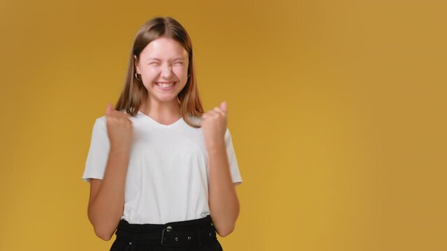Excited teenager. Unbelievable success. Luck achievement. Great news. Portrait of satisfied happy girl in white t-shirt celebrating victory isolated on orange copy space advertisign background.