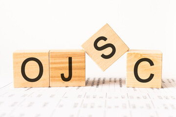 Word ojsc. Wooden small cubes with letters isolated on white background with copy space available.