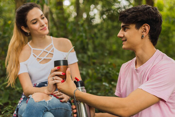 Young couple in love looking at each other - Young couple drinking mate outdoors