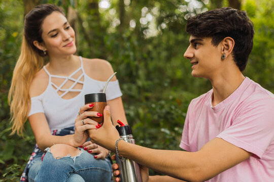 Young couple in love looking at each other - Young couple drinking mate outdoors