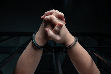 hands in handcuffs behind bars