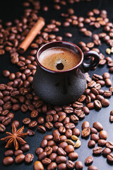 Cup of coffee with a scattering of coffee beans on a dark background
