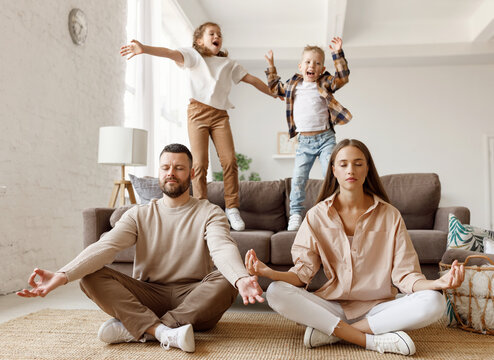 Happy parents  meditating in room with playful kids.