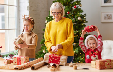 happy family grandmother and grandchildren together wrap Christmas gifts around the Christmas tree...