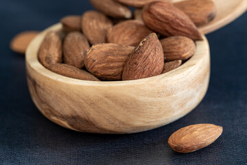 Close-up of almonds in a wooden bowl with a wooden spoon on a black table. eco friendly concept