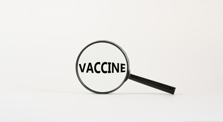 Magnifying glass with text 'vaccine' on beautiful white background. Medical and covid-19 pandemic concept, copy space.