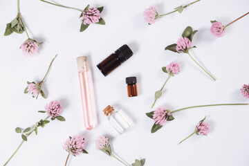 Composition with rose essential oil and flowers on white background, top view
