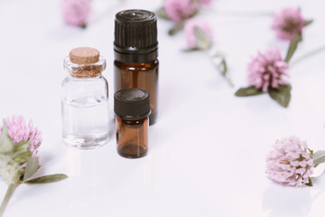 Composition with rose essential oil and flowers on white background, top view