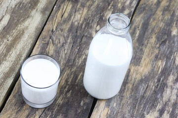 A bottle and glass of milk on a wooden background