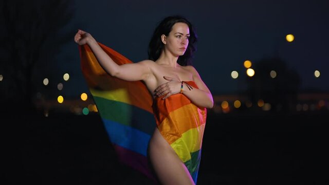 Naked young lesbian woman covers with rainbow LGBT flag