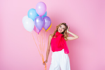 Fototapeta na wymiar elegant happy woman in crown with balloons on pink background