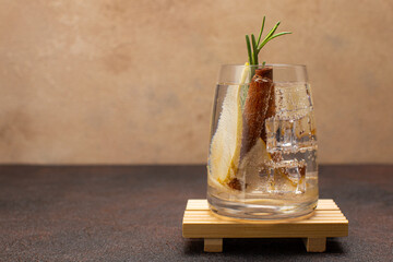 Refreshing pear cocktail with tonic,cinnamon and fresh rosemary on olive wooden board with...