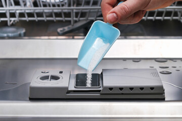 A man pours powder for washing dishes into dishwasher compartment.