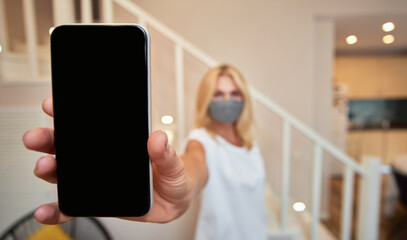 Smartphone in hand of middle aged caucasian woman indoors