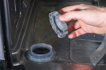 Man opens the container for salt in the dishwasher and fills special salt.
