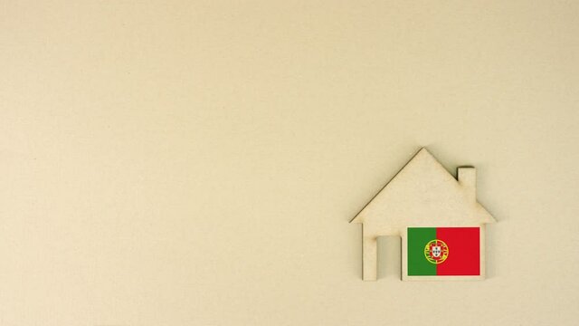 Placing cardboard home icon with printed flag of Portugal. National real estate market concept