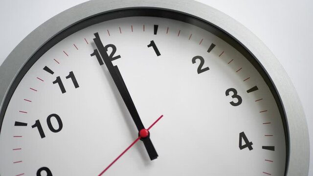 Close up of a white ticking clock on white background, pointing midnight, window reflection, time lapse