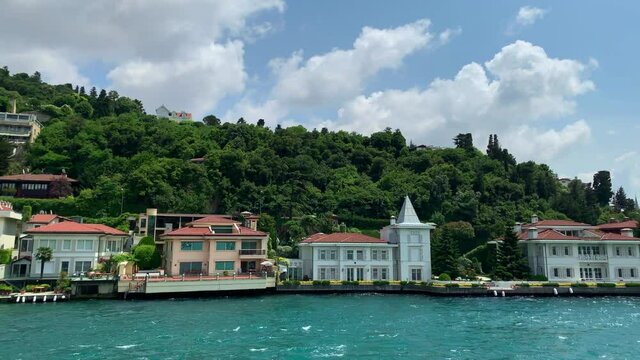 Footage of luxury houses in upscale neighborhood called "Kandilli" by Bosphorus in Istanbul. It is a beautiful summer scene on cloudy summer day. Camera moves forward.