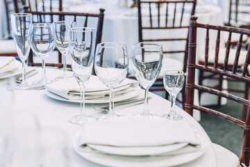 Fancy table set for dinner with napkin glasses in restaurant, luxury interior background. Wedding elegant banquet decoration and items for food arranged by catering service on white tablecloth table.