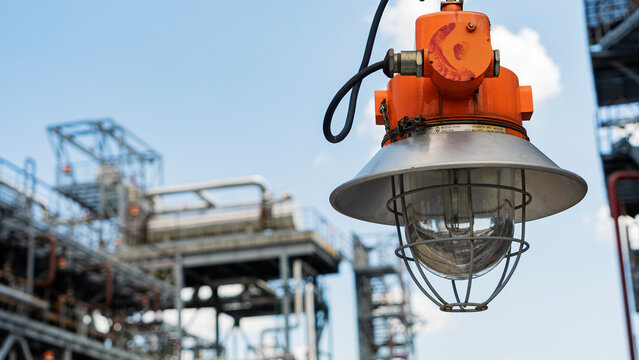 Industrial explosion proof lantern on the background of the refinery plant and classic blue sky. Space for text.