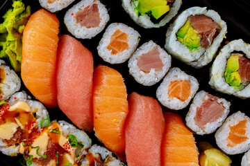 Colorful fresh sushi roll set on a black tray. Japanese food.