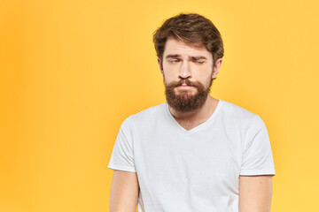 Obraz premium Man in white t-shirt emotions studio gestures with hands displeased facial expression yellow background