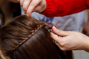 Fototapeta premium Professional braiding of braids by a master hairdresser in a beauty salon. The concept of hair care.