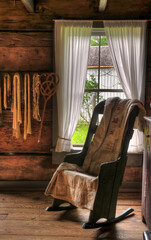 Obraz na płótnie Canvas Old rocking chair and blanket in front of a window of old log house