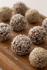 Healthy raw energy balls. Candy vegan balls of dates, coconut pulp in a wooden bowl are laid out in the shape of a pyramid. Top view, concept of useful home-made candies without sugar