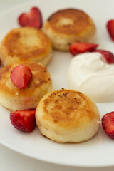 Cottage cheese pancakes or syrniki with Strawberry  on white plate, closeup view. Russian, Ukrainian cuisine. Healthy tasty breakfast
