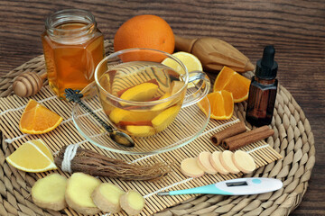 Home made remedy for cold & flu virus with hot herbal drink with fresh fruit & spices, eucalyptus essential oil with thermometer & vitamin C tablets. Immune boosting. 