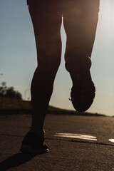 Runner's foot running on the road - Silhouette of legs and feet of women fitness training at sunset.