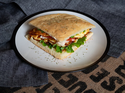 Craft food. Delicious juicy sandwich with chicken, fried egg, tomato and fresh salad.