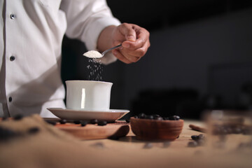 Fototapeta na wymiar Bar keeper pouring coffee powder and sugar into a cup