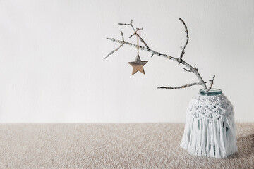 Sustainable, zero waste Christmas natural decoration with white tree branch in macrame vase and wooden Christmas tree toy star. Xmas simple minimalist elegant design with natural elements
