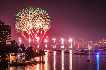 Fireworks reflect off the waters of the Charles River in Boston